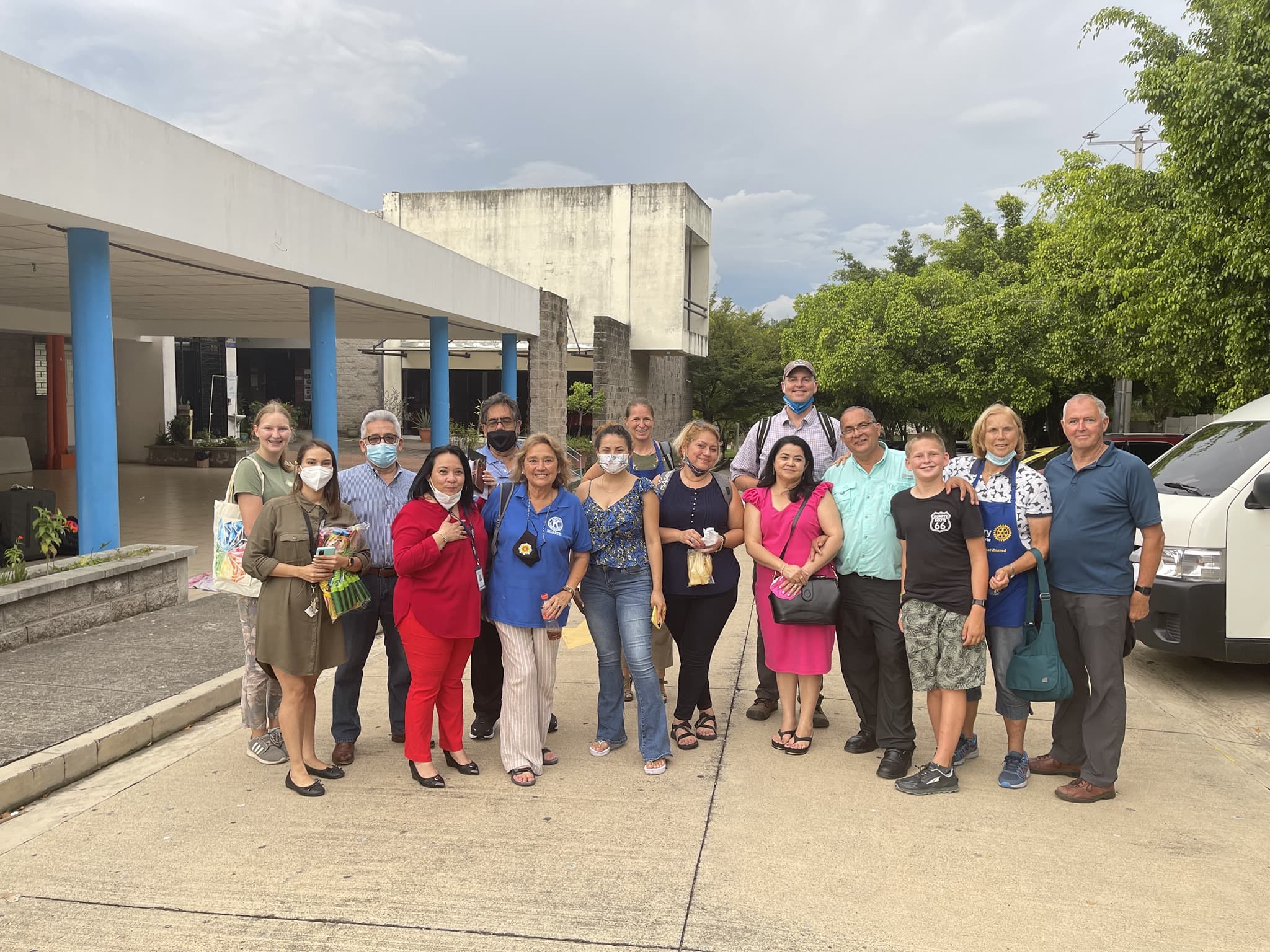 Diverse group of people posing for a photo outside a building with blue pillars.